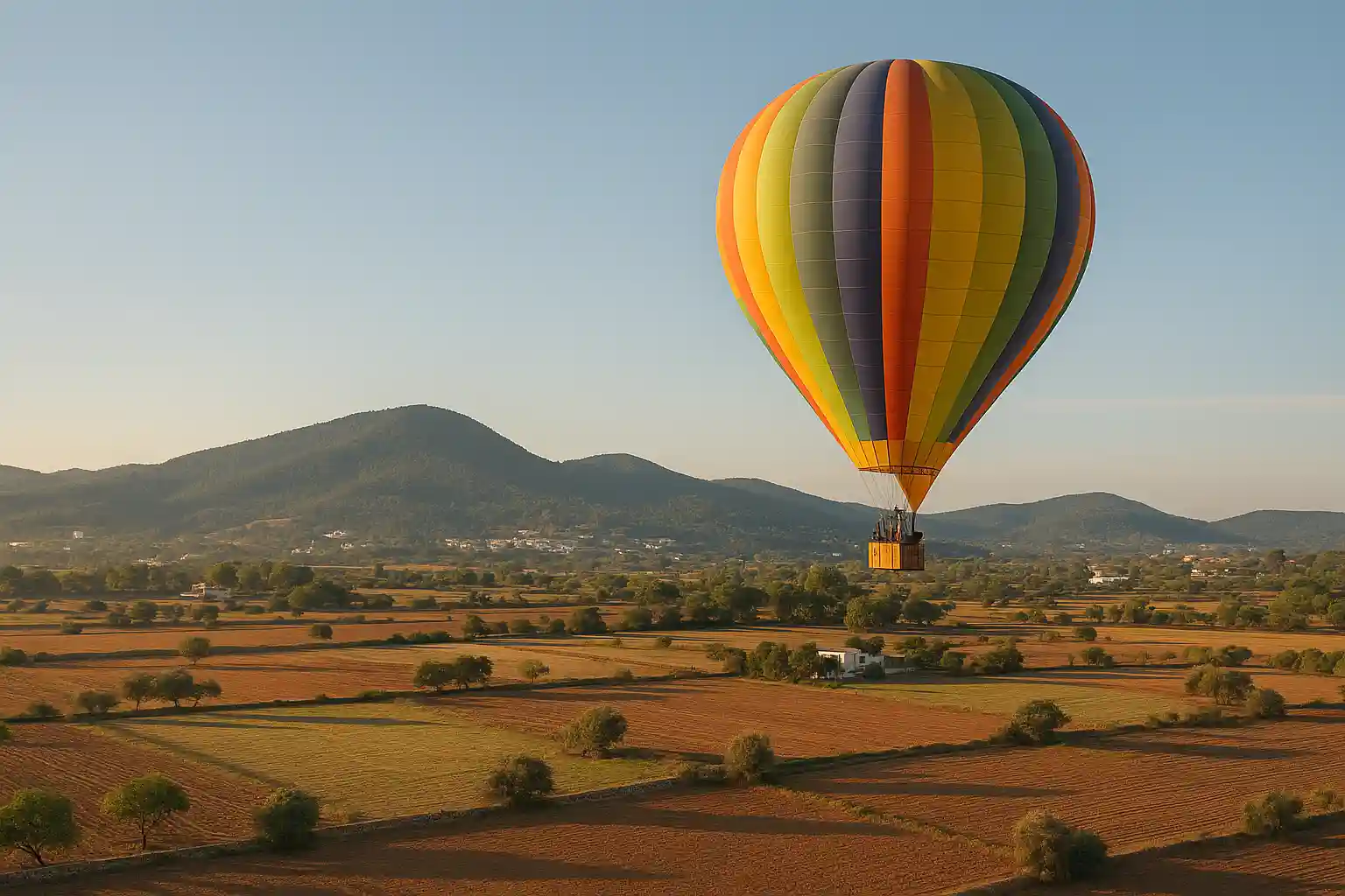 Hot air balloon floating over Ibiza at sunrise with sea and countryside below